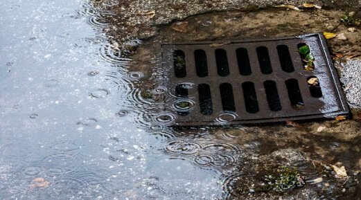 A flooded catch basin overflowing with water